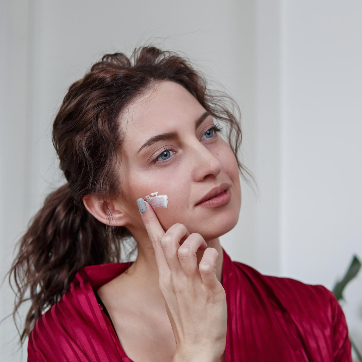 Woman touching her smooth, clear skin with a smile.