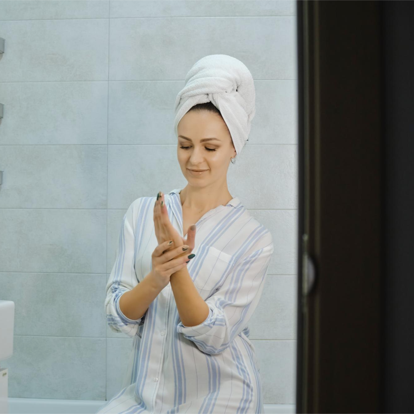 Woman applying cream with a joyful smile and glowing skin.