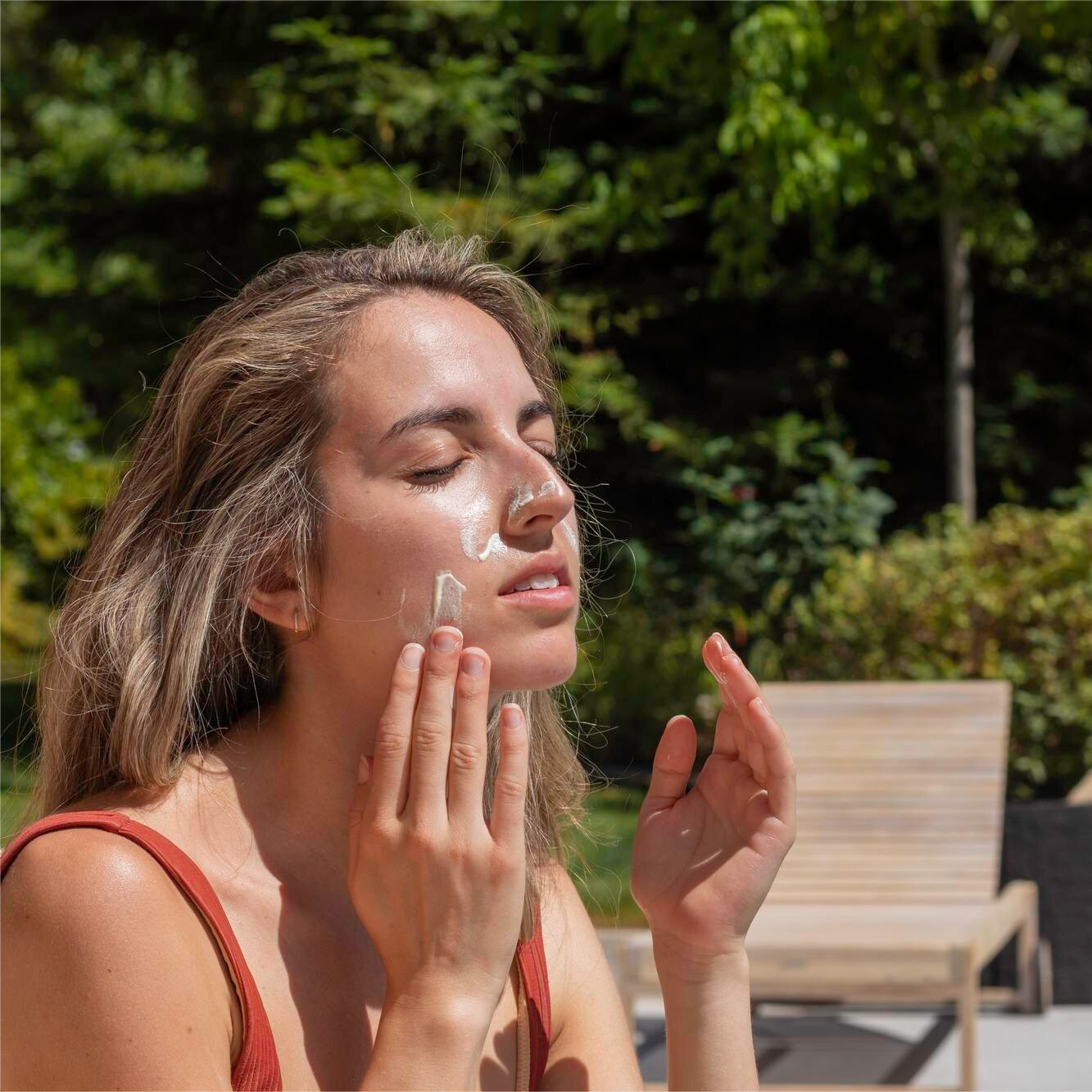 Close-up of woman gently applying cream on her face.